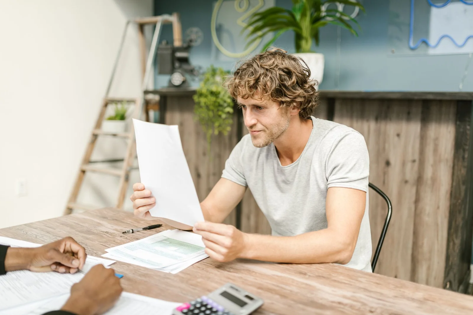 Une personne consulte ses documents administratifs à une table, lumière naturelle